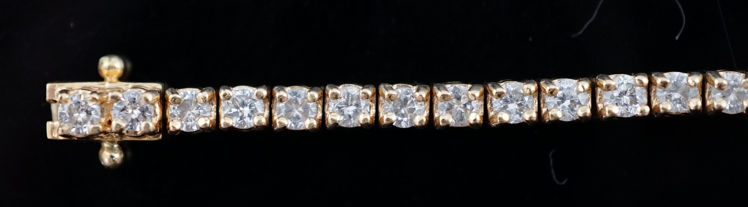 A modern 18ct gold and fifty nine stone round brilliant cut diamond set line bracelet
